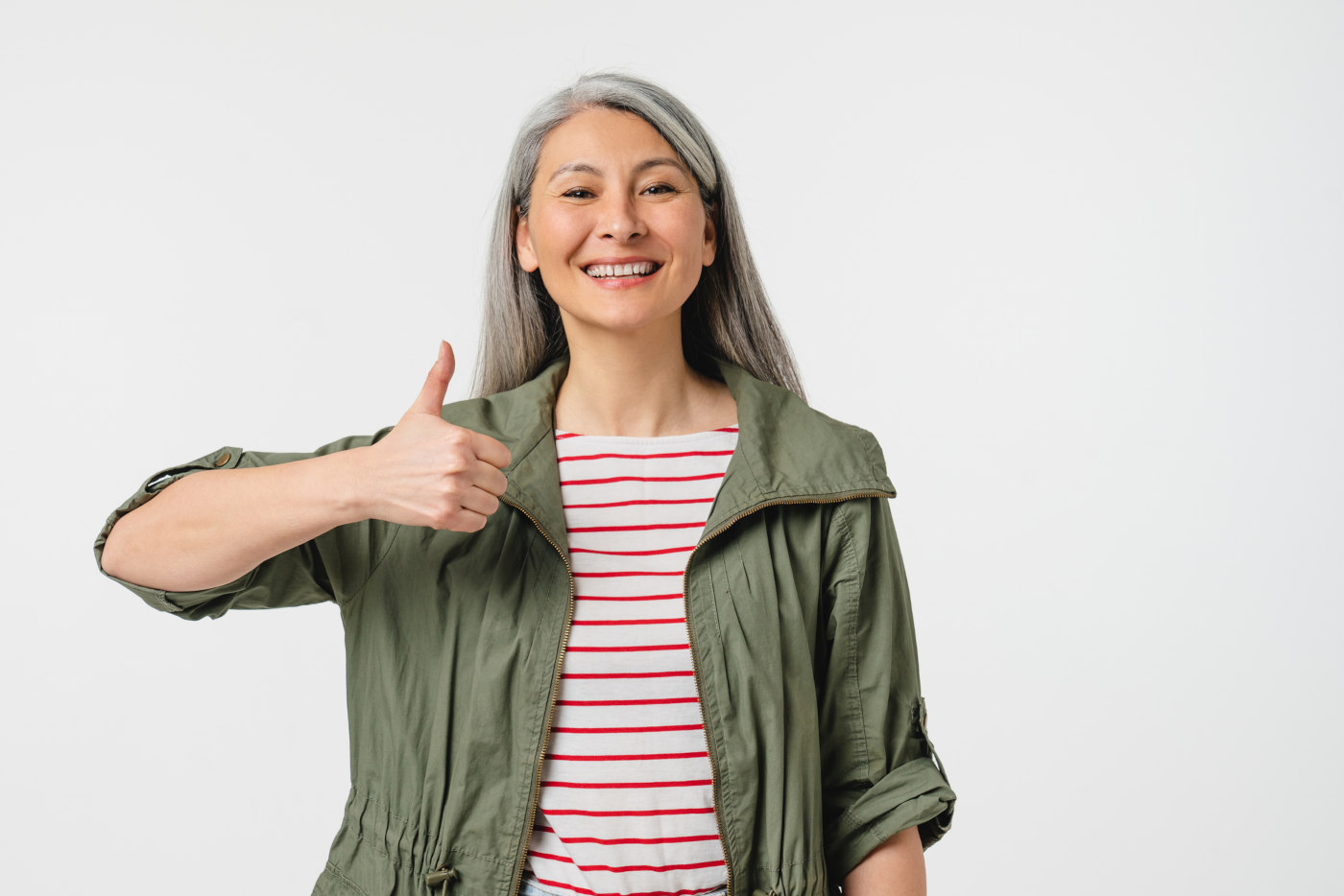 Positive smiling happy mature middle aged woman with grey hair showing thumb up looking at camera isolated in white background. Good job! Great! Well done!